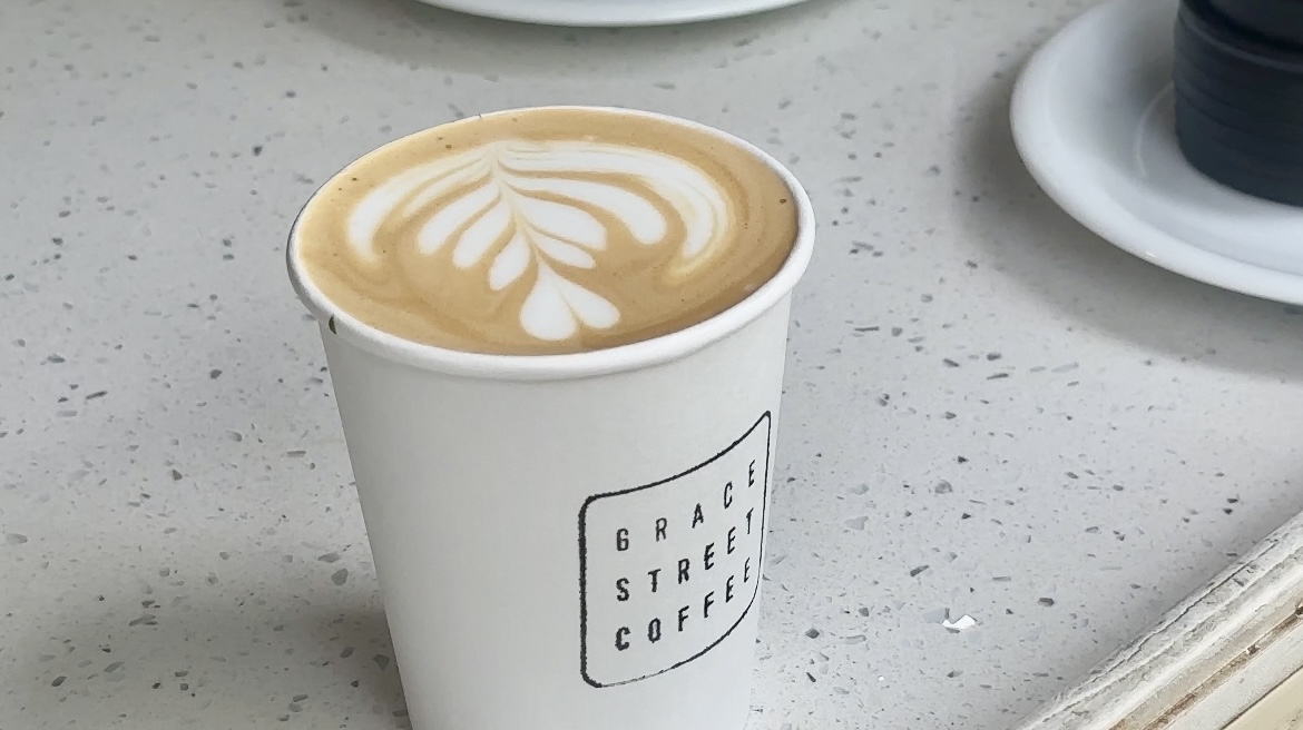 Close-up of espresso latte art on Grace Street Coffee branded cup.