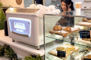 View of barista preparing a drink behind the chic Gaggia espresso machine on the counter at Coffeefi Roastery in Bethesda