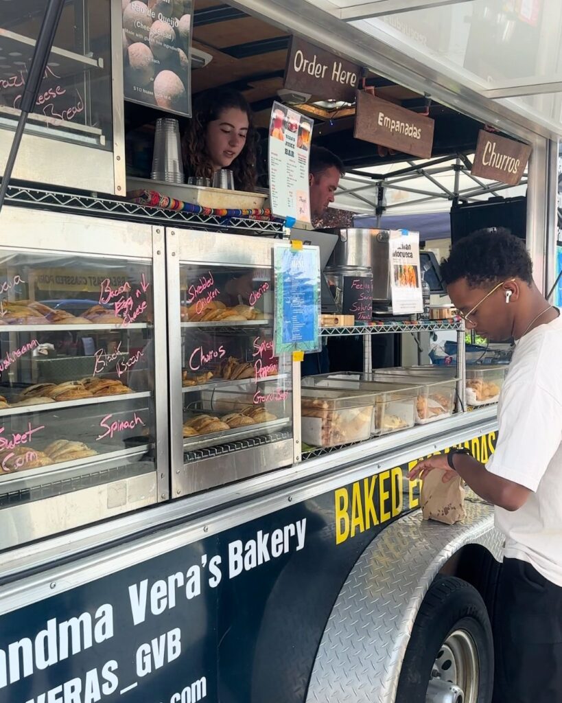 Food truck service window showing empanada flavors and churros sign at Bethesda market