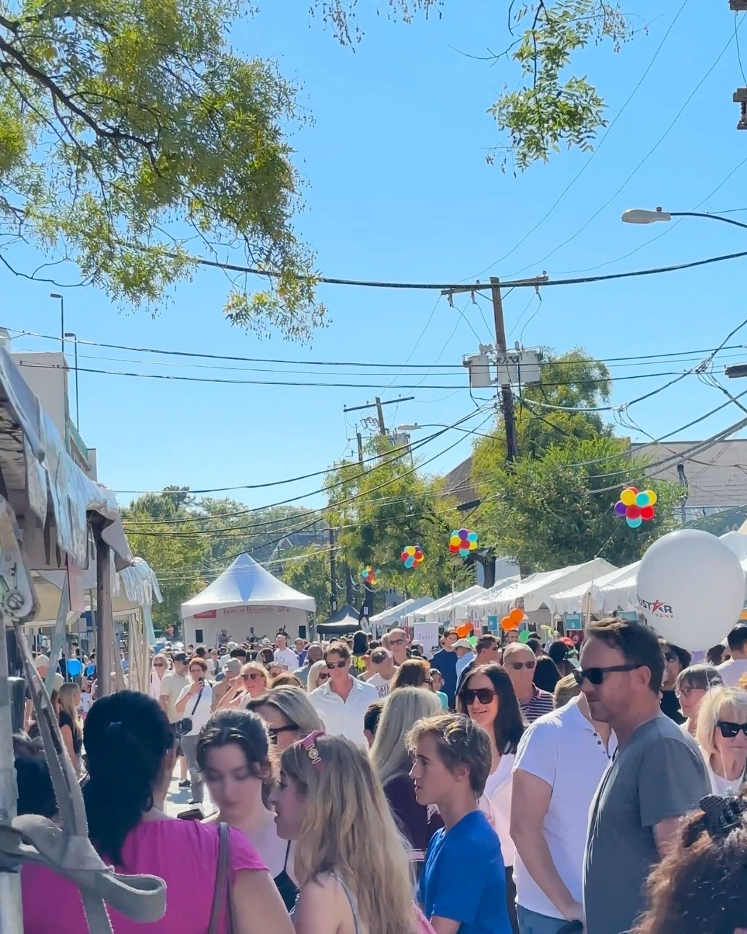 Festival attendees walking between restaurant vendor tents and bright floating balloon decor