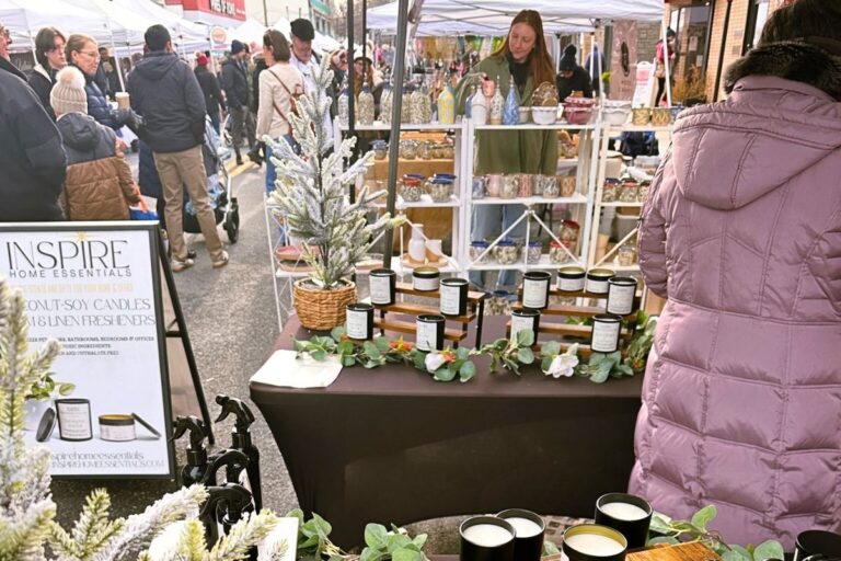 View of the holiday market street standing in front of a vendor's homemade candle display