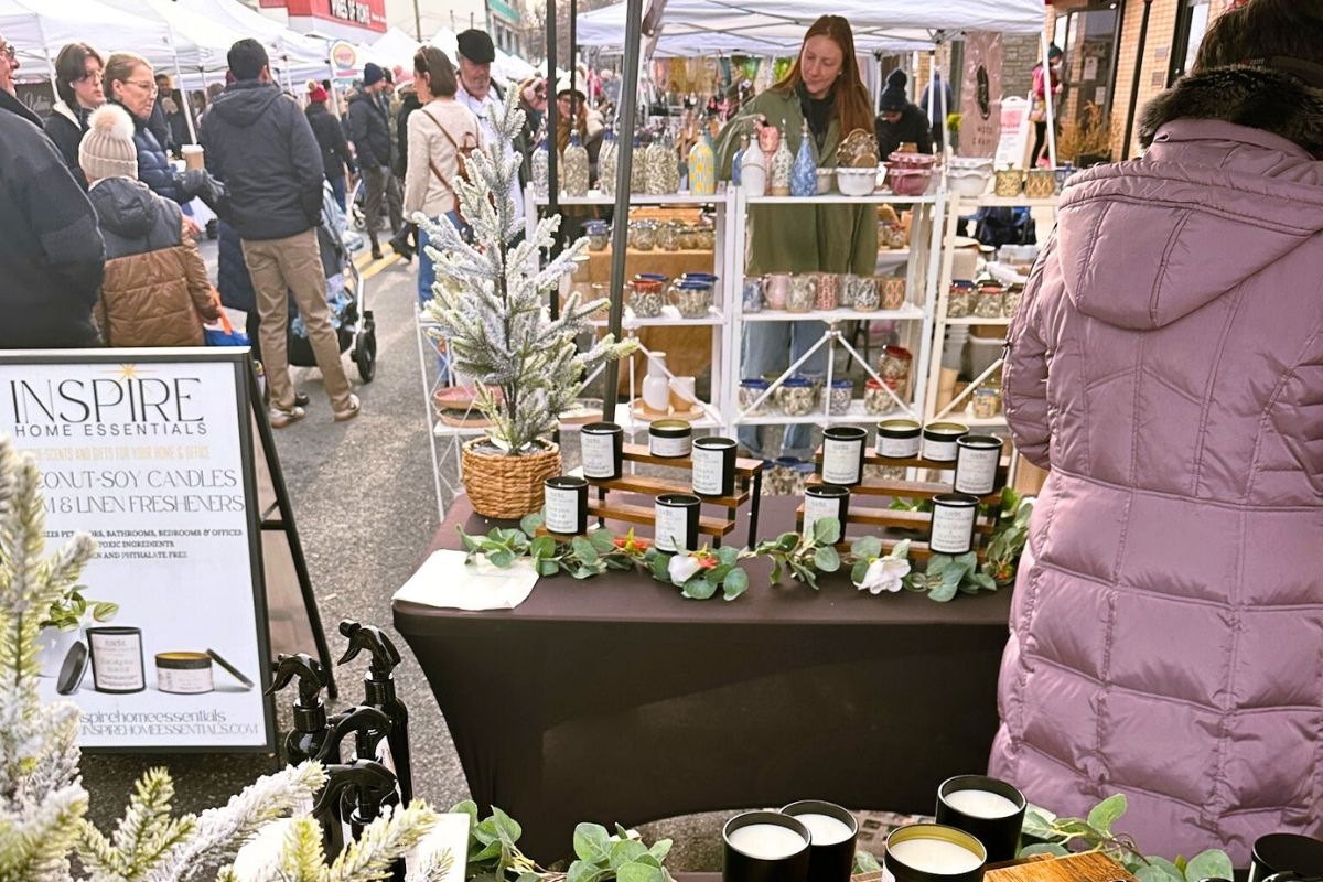 View of the holiday market street standing in front of a vendor's homemade candle display