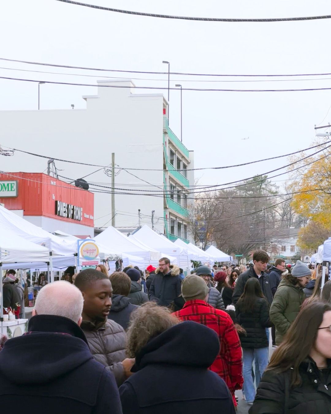 Crowds browse white vendor tents at downtown Bethesda holiday market.