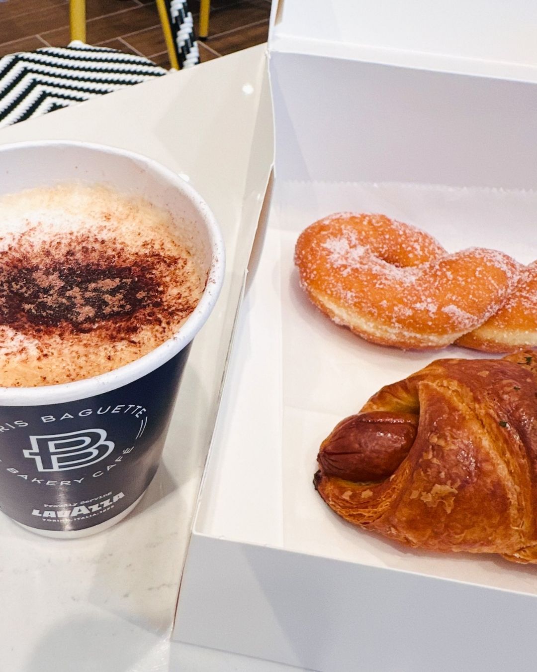 Coffee cup with sausage-filled croissant and sugared twisted donut at Paris Baguette Bethesda