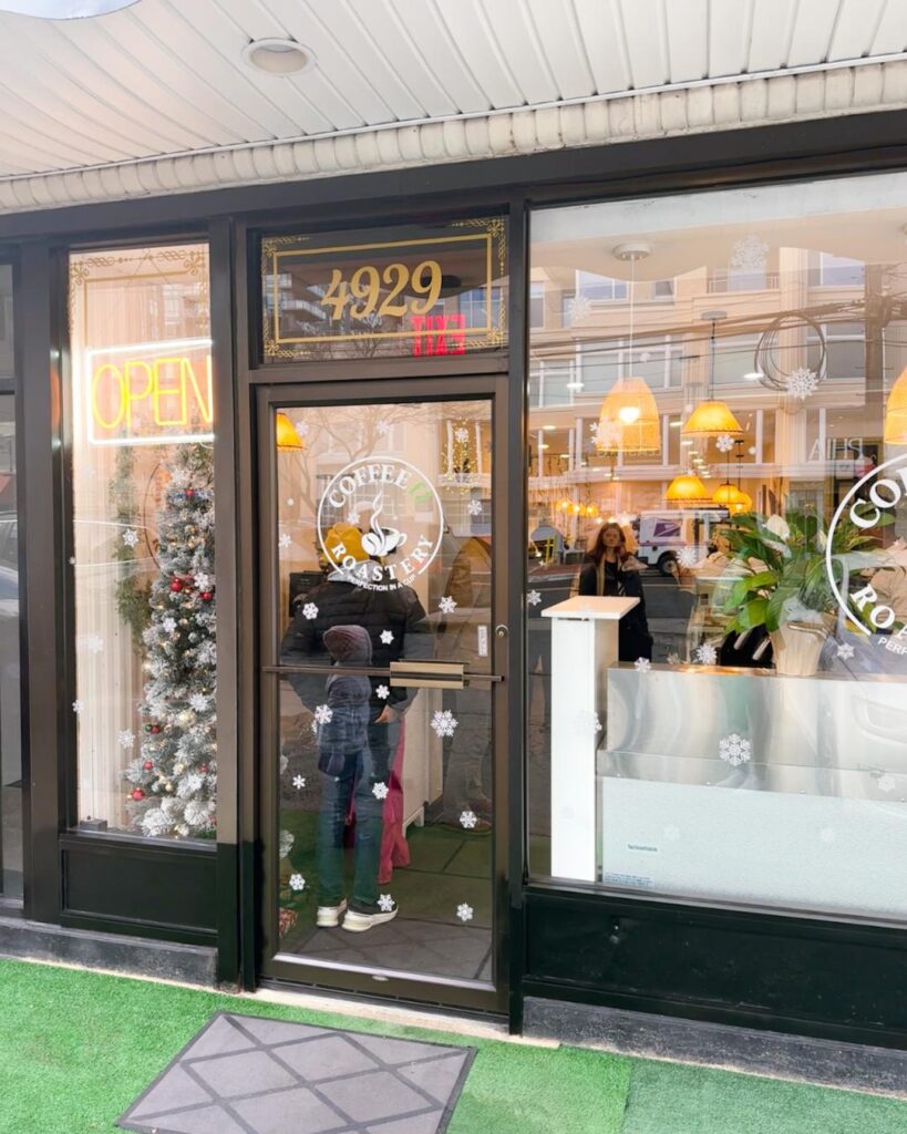 Exterior storefront of Coffeefi Roastery on St. Elmo Avenue in Bethesda featuring holiday window decals and a neon open sign