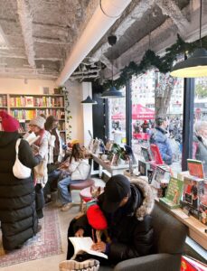 Customers reading on plush seating by the windows with a view on Norfolk Ave, and families browsing at Wonderland Books