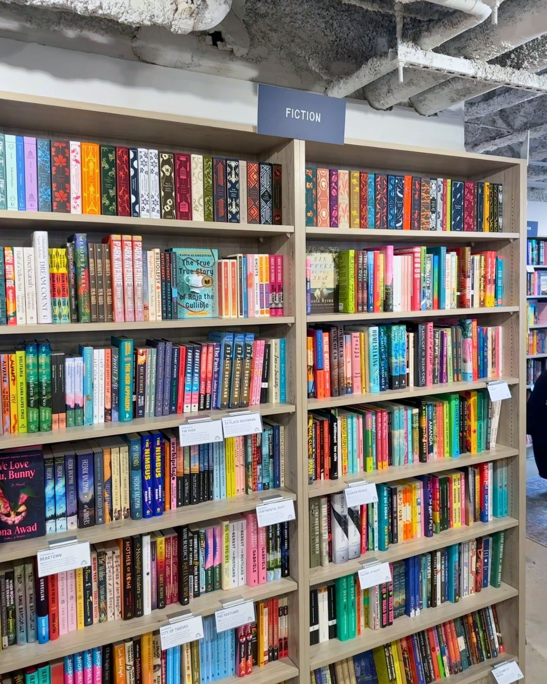 Fiction section at Wonderland Books with floor-to-ceiling shelves organized by genre signs