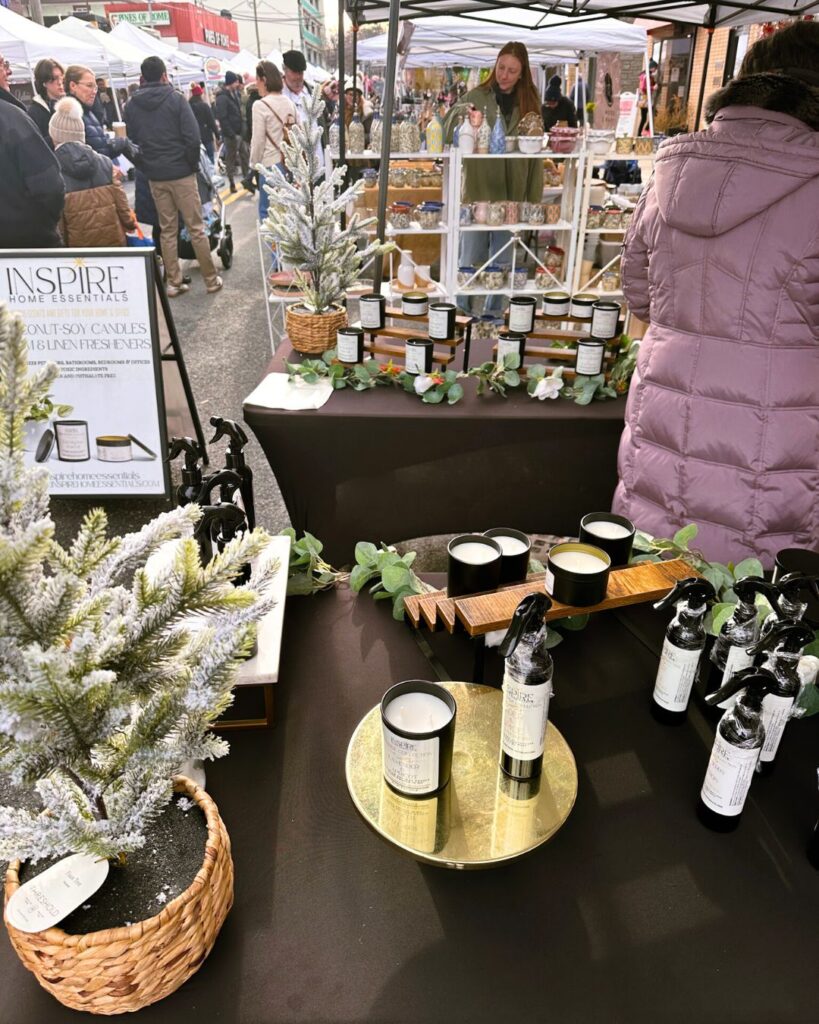 Inspire Home Essentials candles and scented sprays next to decorative frosted mini trees.