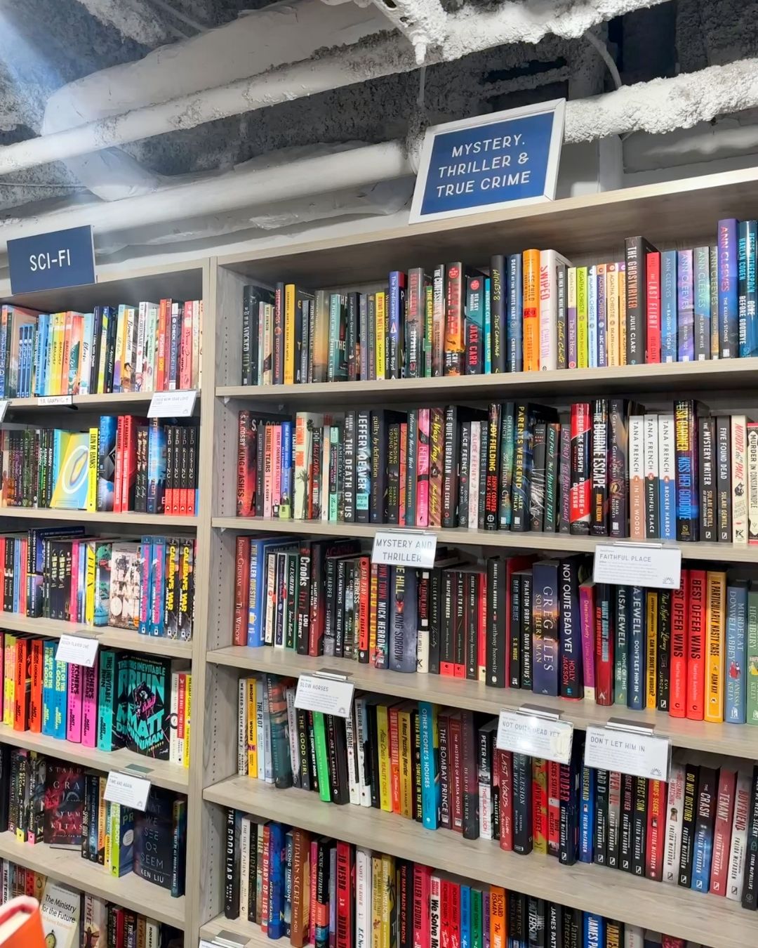 Mystery, Thriller, and Sci-Fi bookshelves with blue signage at Wonderland Books in Bethesda