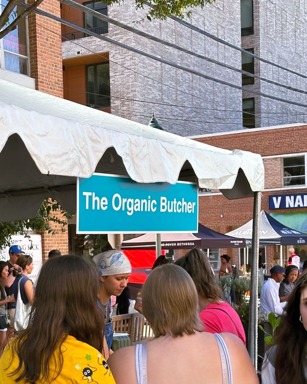 The Organic Butcher booth sign with attendees waiting in line at annual festival