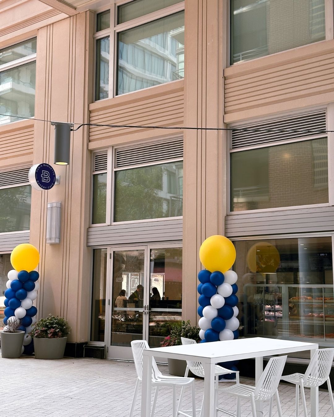 The Fairmont Avenue storefront with outdoor seating and blue, white and yellow grand opening balloons
