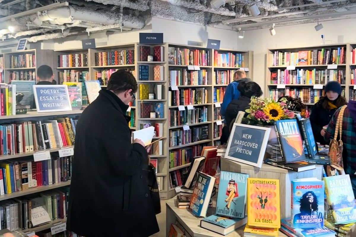 Interior of Wonderland Books in Bethesda with exposed ceiling, pendant lights, and shoppers browsing near the front window