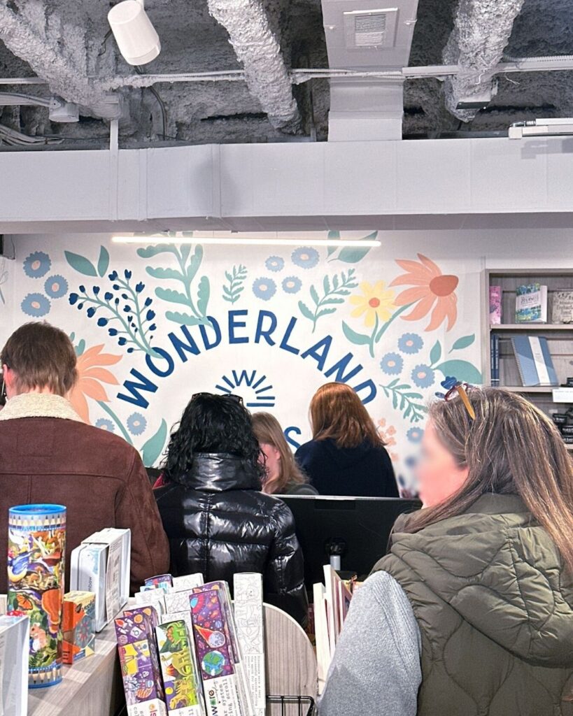 Wonderland Books mural with floral design and shoppers at the checkout counter